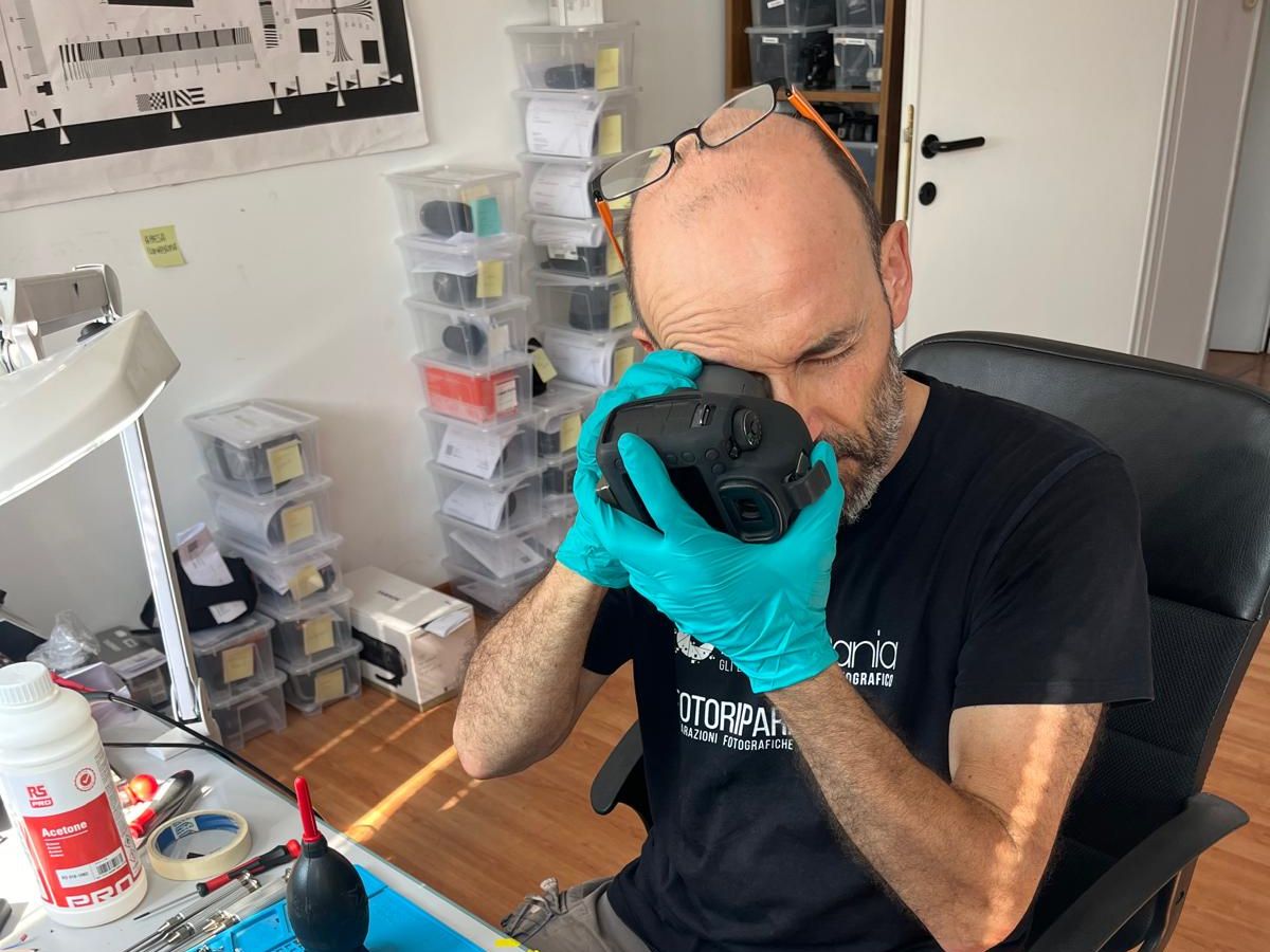 Technician inspecting a camera body through the viewfinder during a full check-up at the Ancona lab